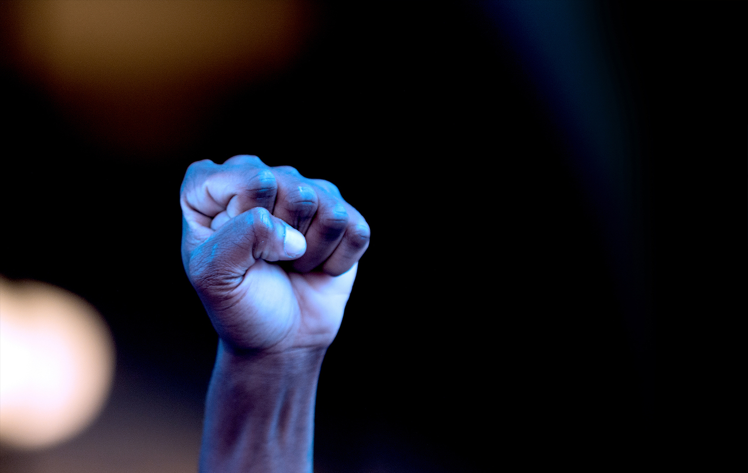 Protester fist in the air against a dark background